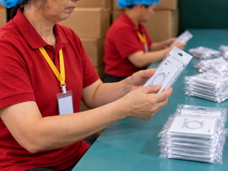 袋に入った商品を手に取って確認するスタッフ